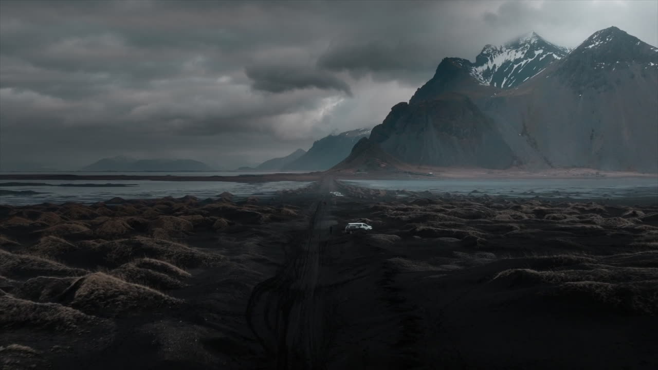 imágenes de drones sobre la playa de arena negra de stokksnes, mostrando nubes dramáticas y la majestuosa montaña vestrahorn, islandia