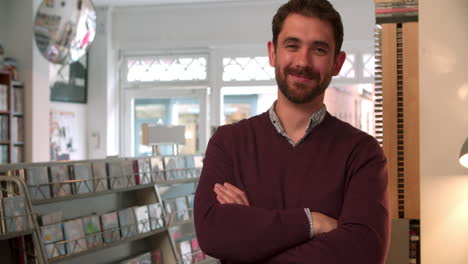 el dueño de la tienda posando en una tienda de discos, sonriendo