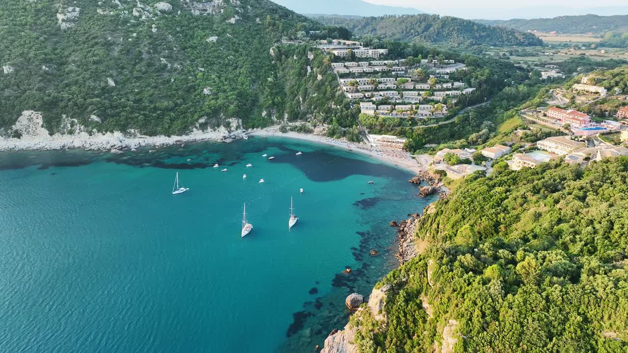 playa de liapades en la isla de corfú con veleros y aguas azules claras, rodeada de exuberante vegetación, vista aérea