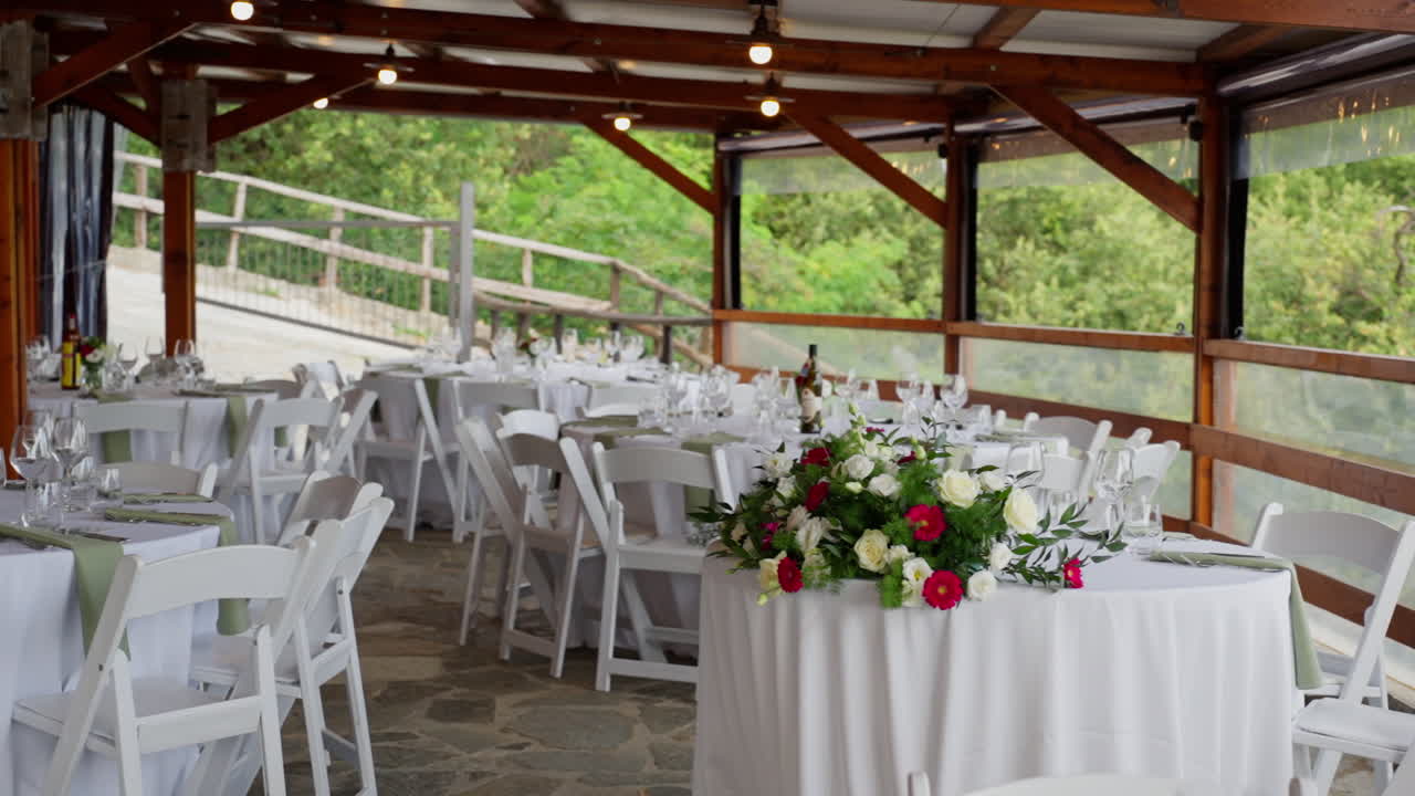 Panning at wedding reception, white tables decorated with flowers in countryside location with no people, nobody
