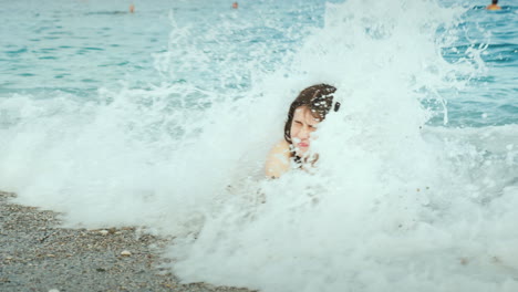 a young woman is having fun on the seaside sea waves cover her with her head