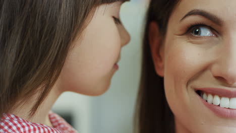 Close-Up-View-Of-Cute-Girl-Whispering-Some-Secret-To-The-Ear-Of-Her-Young-Mother
