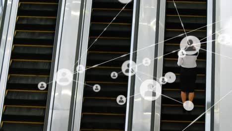 Animation-of-network-of-connections-with-icons-over-businesswoman-on-escalator