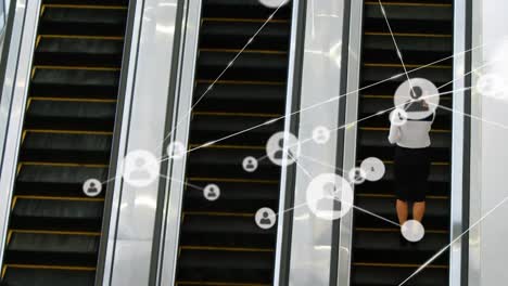 animación de una red de conexiones con iconos sobre una mujer de negocios en una escalera mecánica