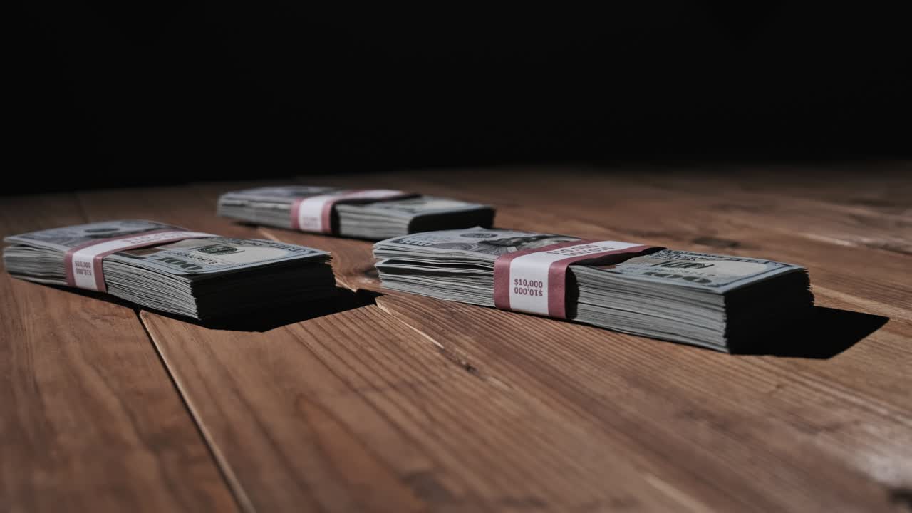 Three Stacks of 10000 American Dollars Banknotes in Bundles Lie on Wooden Table