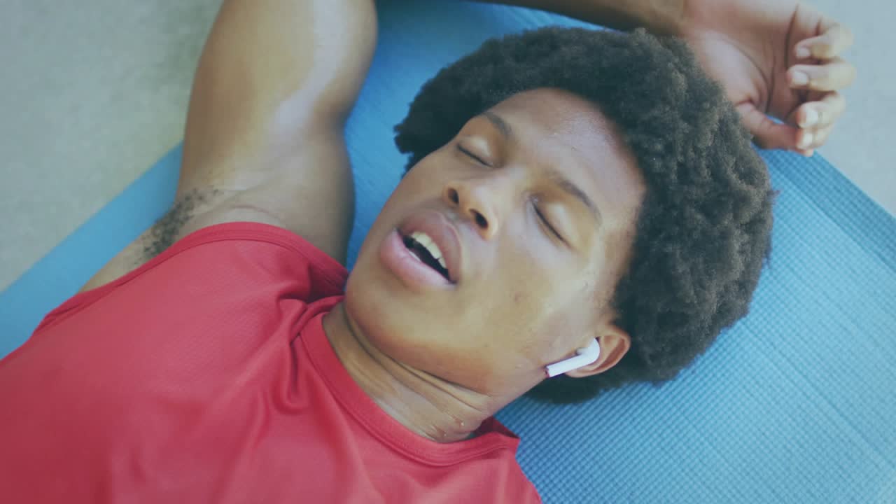 Mand, der ligger på en blå måtte efter træning og gnider sig i øjnene, mens grafikken GOD STEMNING fjernes for fitness