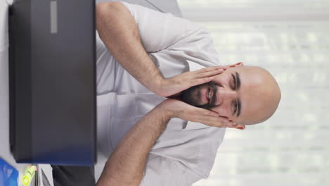 Vertical-video-of-Home-office-worker-man-looks-at-camera-with-happy-and-smiling-face.