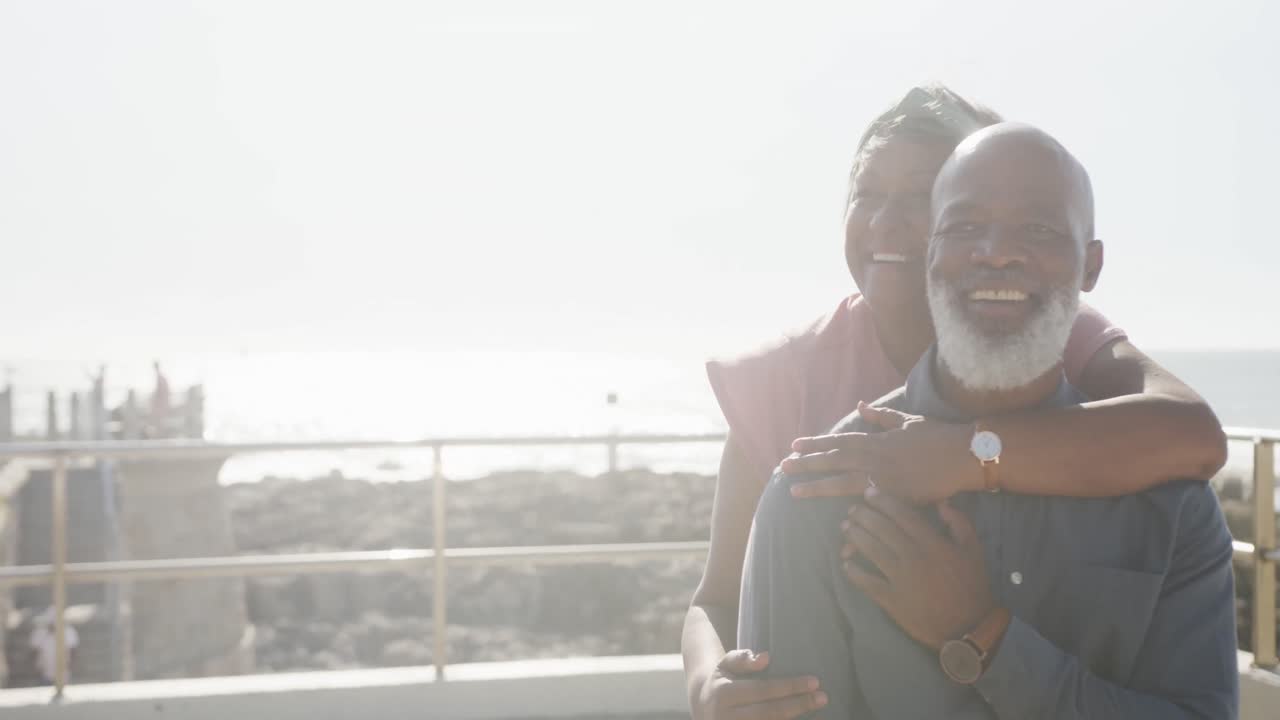 una feliz pareja de ancianos afroamericanos abrazándose en el paseo marítimo, espacio de copia, cámara lenta