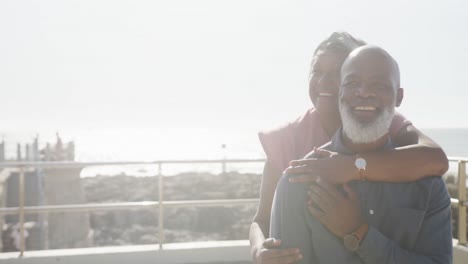 Happy-senior-african-american-couple-embracing-on-promenade-by-the-sea,-copy-space,-slow-motion