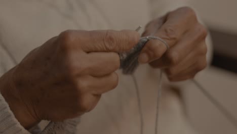 primer plano en cámara lenta de una anciana usando ganchos de tejer para hacer un cuadrado