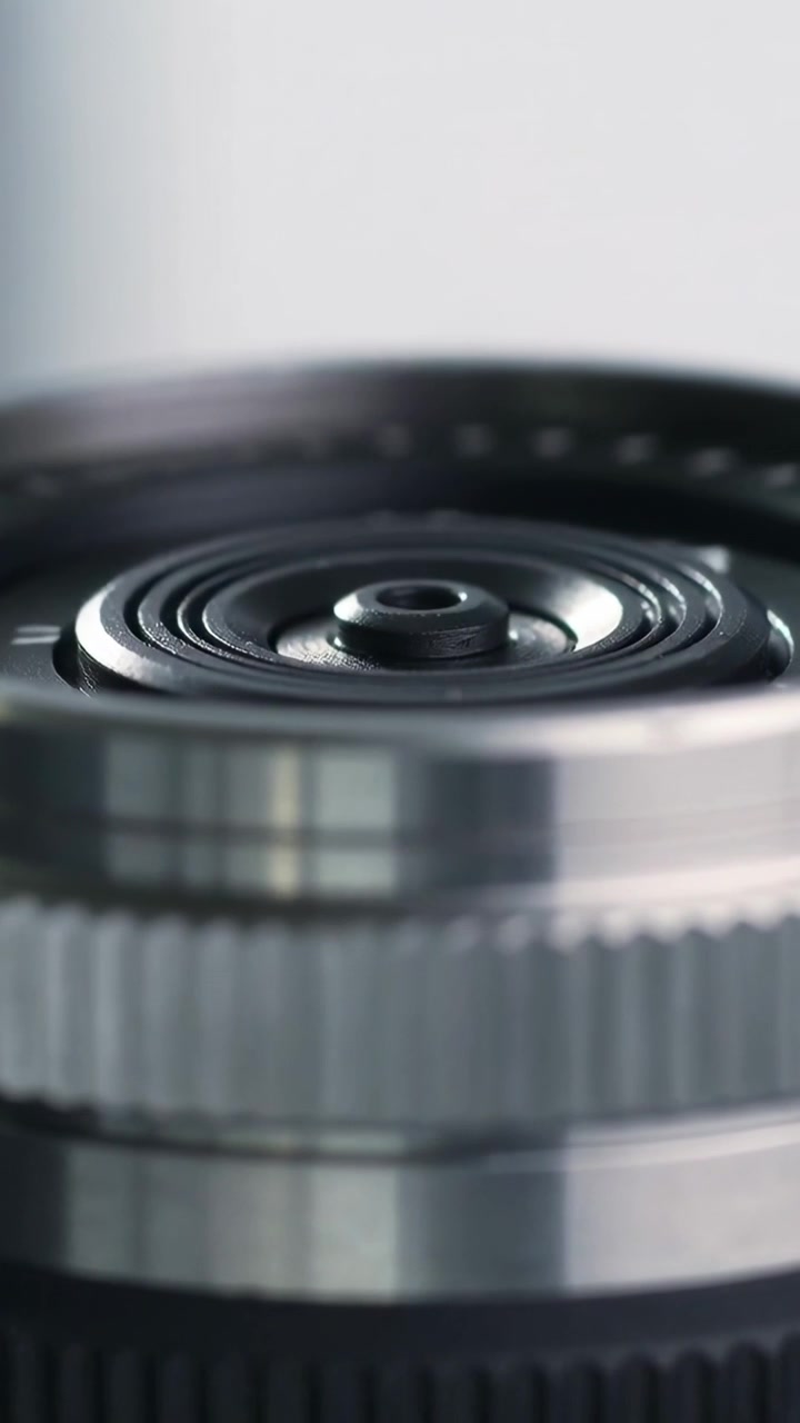 Vertical video: Shifting focus plane, lens barrel revealing aperture and window glint in studio