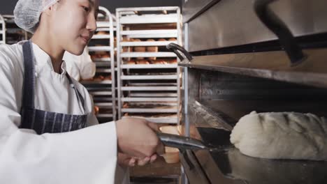 Diversos-Panaderos-Trabajando-En-La-Cocina-De-La-Panadería,-Poniendo-Pan-En-El-Horno-En-Cámara-Lenta