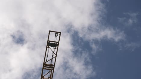 Ende-Eines-Baukrans-Von-Unten-Gegen-Den-Blauen-Himmel-Und-Vorbeiziehende-Wolken-Gesehen