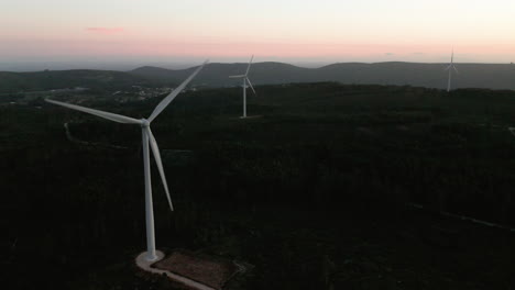 wind turbines producing energy with silhouettes at the background in serra de aire e candeeiros, leiria portugal. - aerial shot