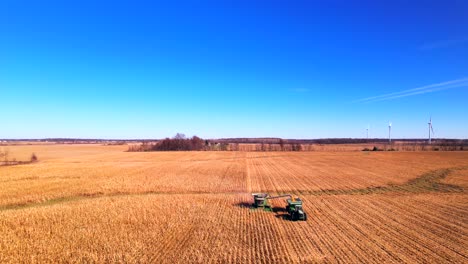 heavy machinery harvesting corn on farm in sunny day