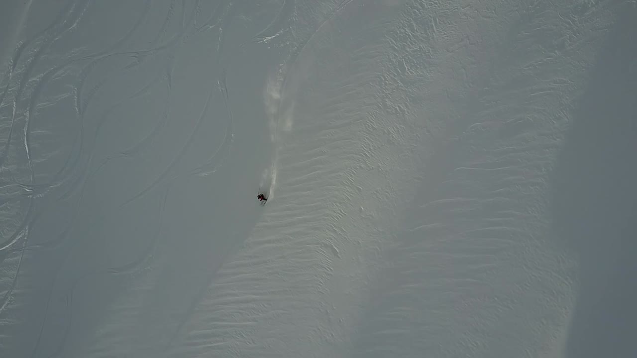 tomada de un avión no tripulado de un esquiador bajando por una pendiente de polvo en el backcountry