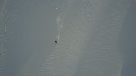 drone shot of skier going down powder slope in backcountry