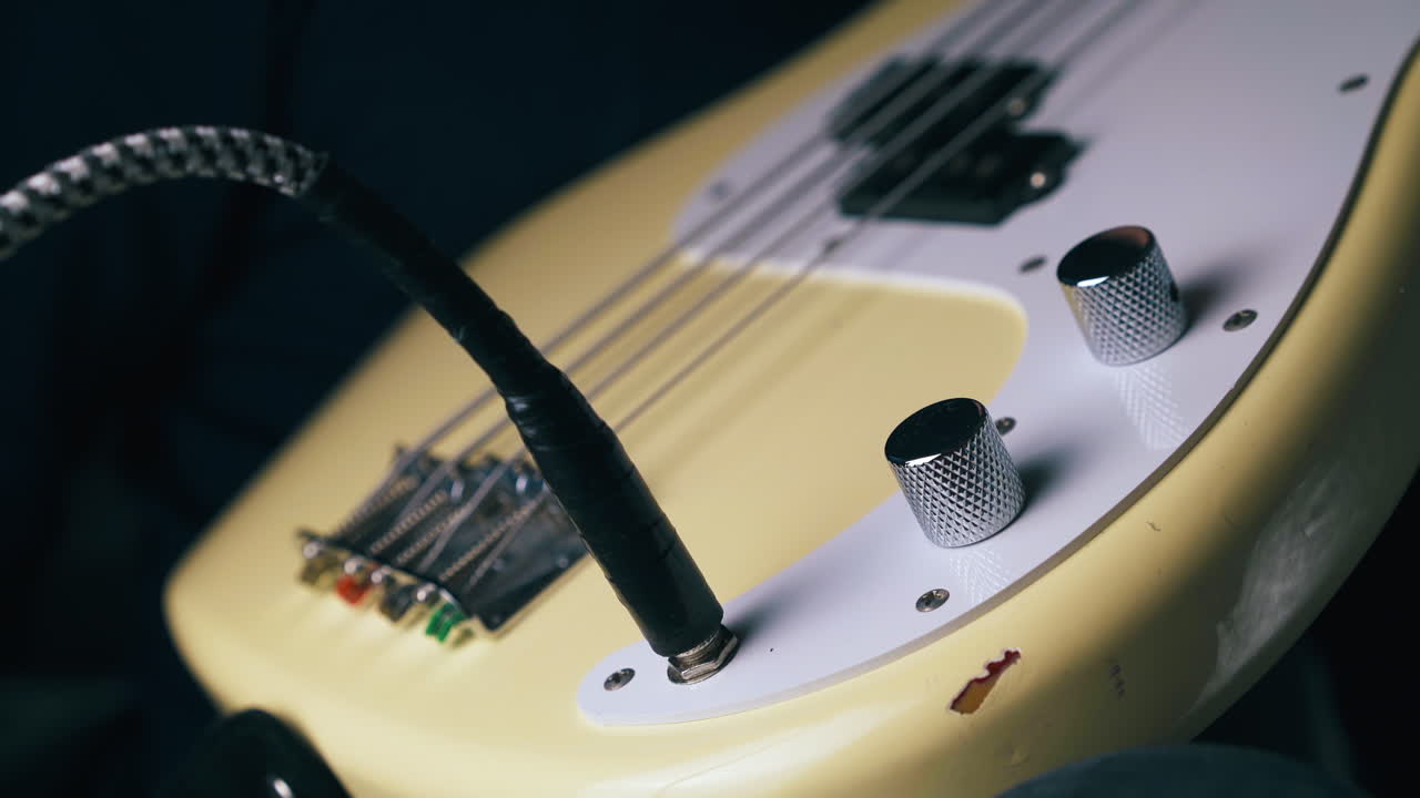 el guitarrista conecta el amplificador al bajo. la guitarra gira las perillas.