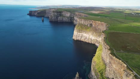 drone shot of the cliffs of moher and the irish farmland at sunset