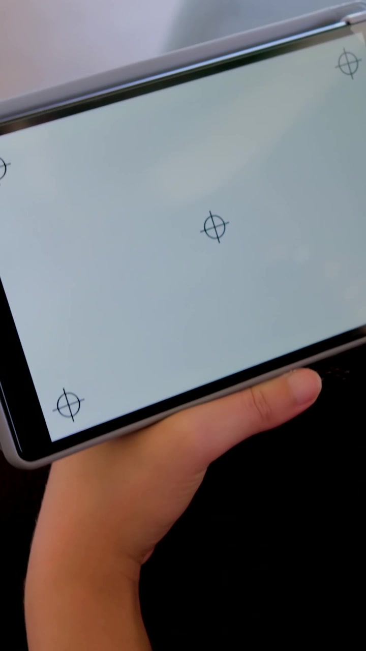 Video verticale: Donna con manica marrone che ruota, che inclina il tablet sul divano dopo un tocco, calibrando gli obiettivi.