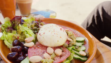 Un-Plato-De-Deliciosa-Ensalada-En-Un-Café,-Mostrando-Los-Sabores-Mediterráneos-Con-Lechuga,-Tomate,-Nueces-Y-Mozzarella