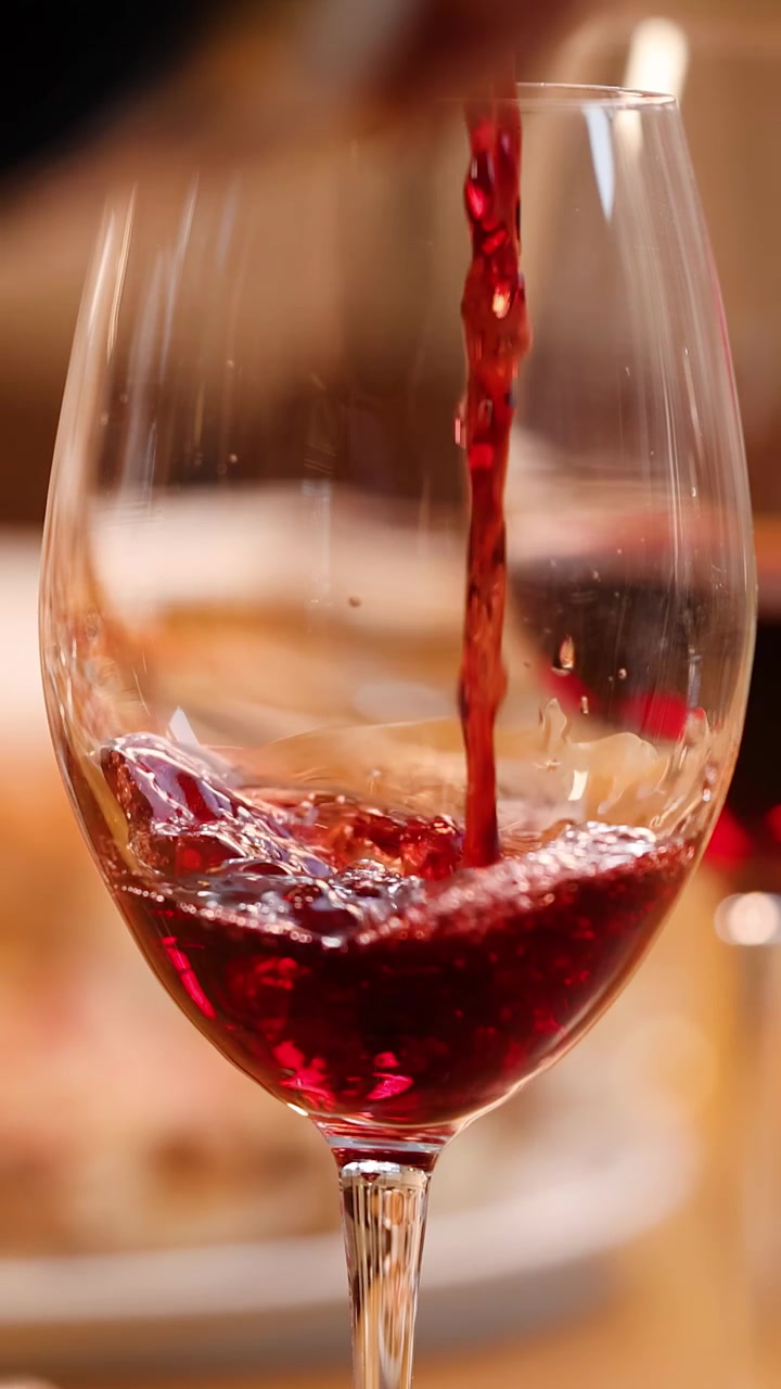 Primo piano di vino rosso versato in un bicchiere di cristallo su un tavolo di ristorante.