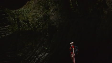 una mujer explorando una cueva oscura.