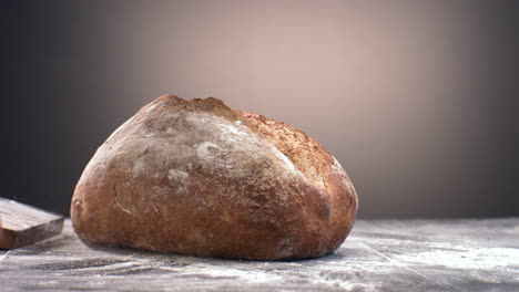 super slow motion freshly baked loaf of bread falling on a table covered with flour. shot with high speed camera at 420 fps