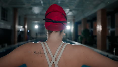 a woman stands by a swimming pool, ready to compete in a swimming competition.