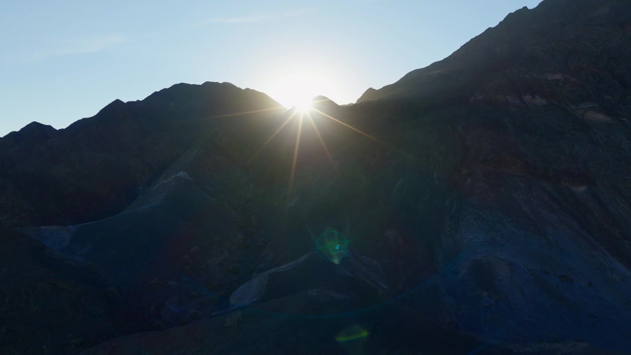 reveal dron shot of sun rays during sunrise over big rocky mountain in argentina