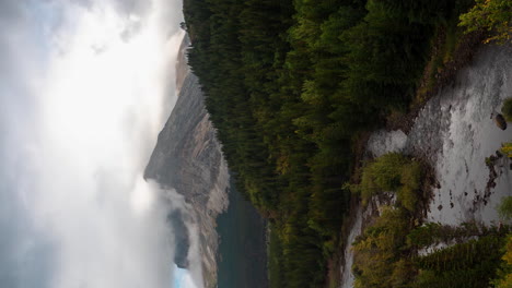 vertical 4k time lapse, dramatic clouds above majestic pristine mountains landscape forest, glacial river and peaks