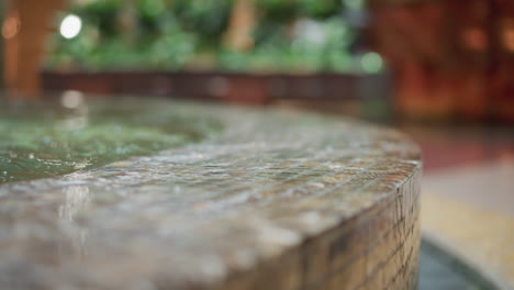 primer plano de agua que fluye por el borde de la fuente de azulejos de mosaico con un fondo suavemente borroso con luz ambiental y toques de vegetación