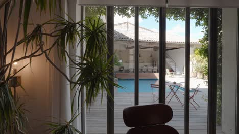 dolly shot revealing a private pool in the garden of a villa through a french door