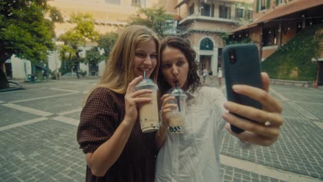 two friends enjoying bubble tea in a city square