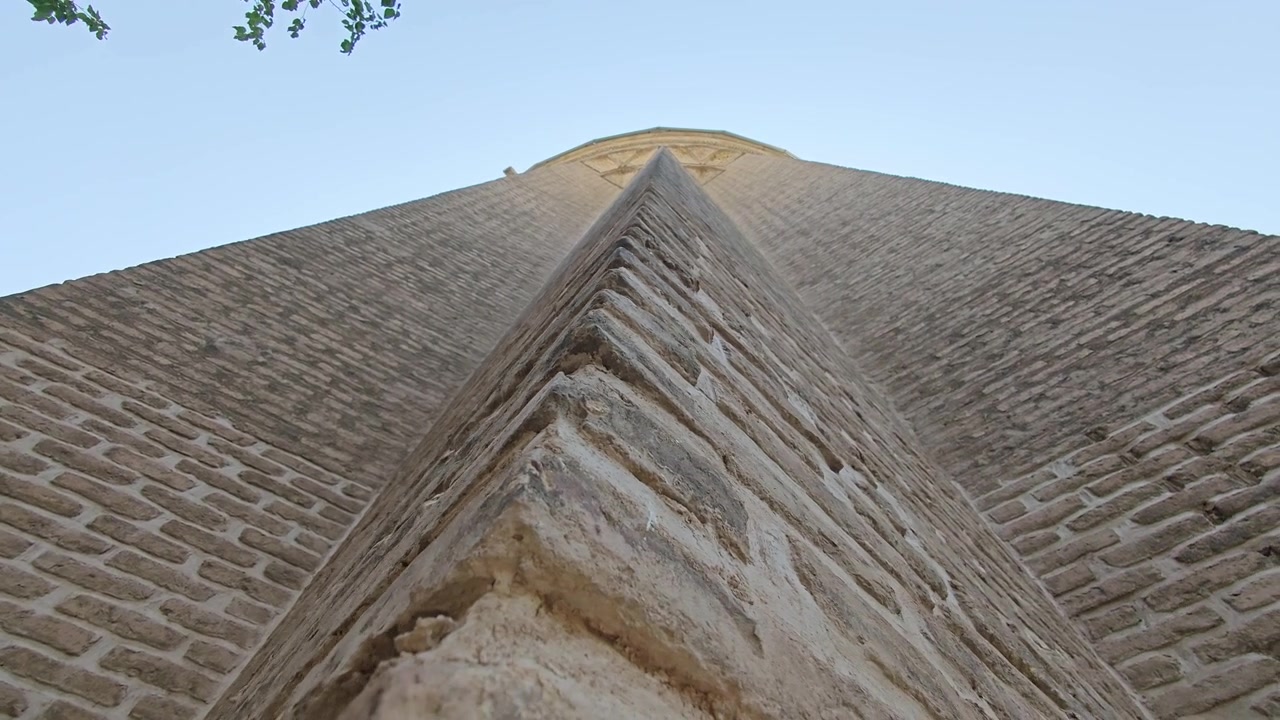 Pohled zdola na vysoký starobylý cihlový minaret