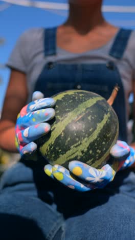 mujer sosteniendo una calabaza en el jardín