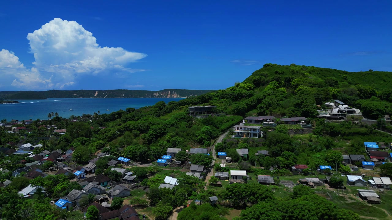 Moderna villa di lusso adagiata su una collina verde, con piscina e ampie vedute della baia e della città locale. Bella vista aerea con panorama inverso da drone.