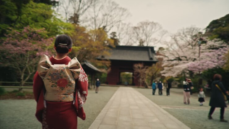 Donna in kimono al tempio giapponese con fiori di ciliegio