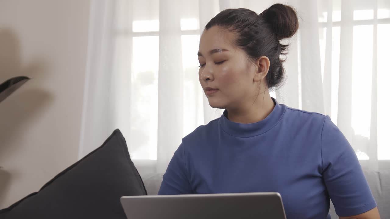 새로운 평범한 여성 사업가는 행복하게 소파에 앉아 노트북으로 집에서 일합니다