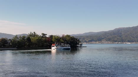 tour boat sailing on a sunny day, surrounded by birds, towards the asoumi sea in amanohashidate, kyoto, japan