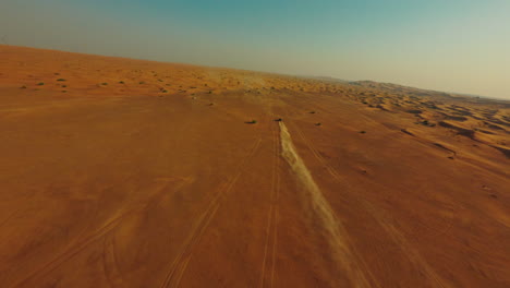 drone shot of atv four wheeler vehicle moving in landscape of dubai desert uae