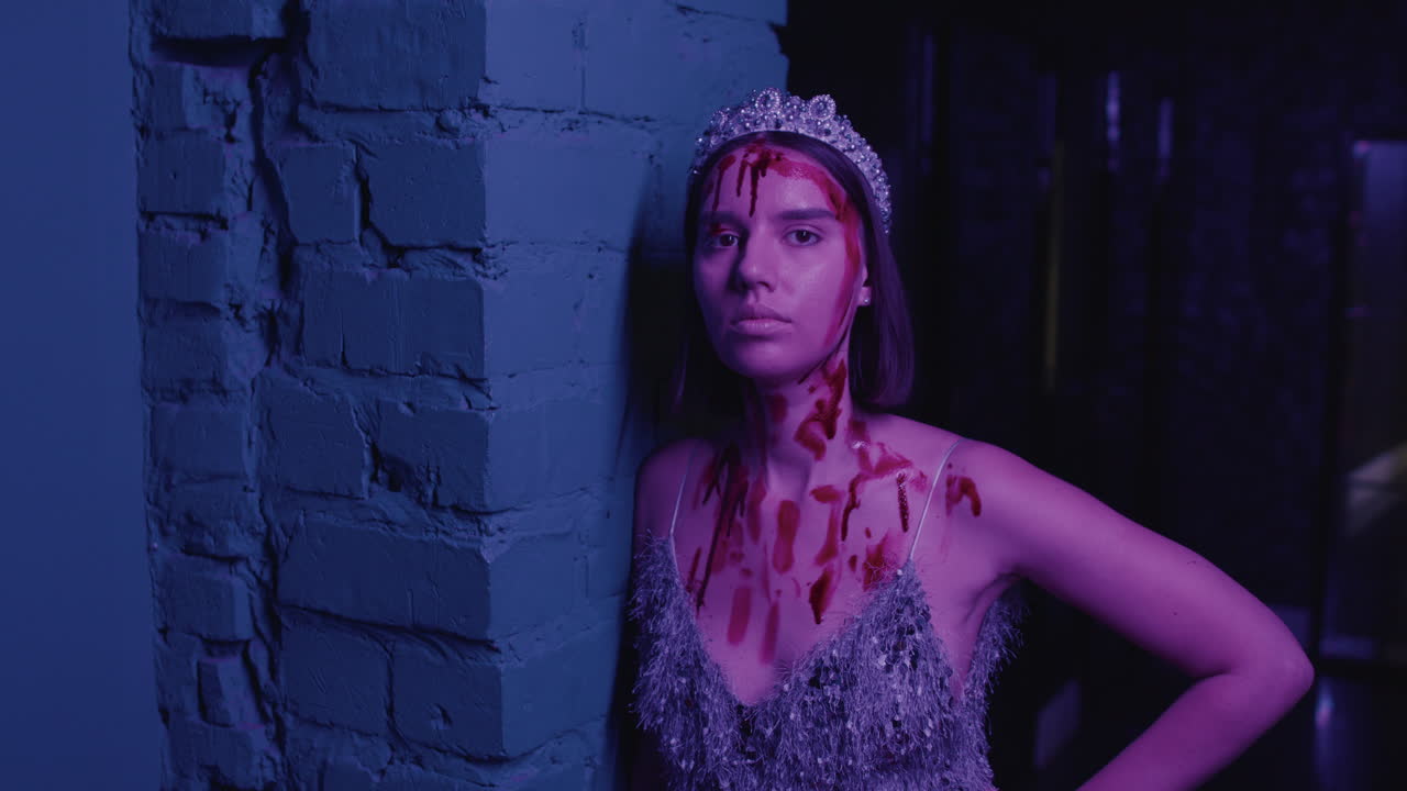 젊은 여성이 벽돌 벽에 있는 카메라를 보고 있습니다.