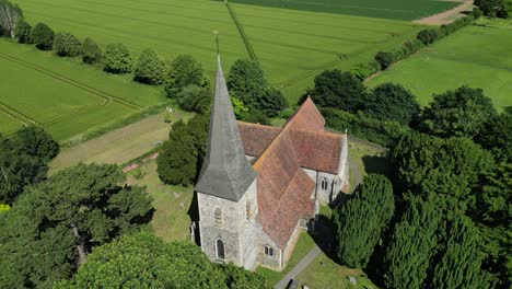 a slow aerial arc shot of st john the evangelist church in ickham, kent, during a bright summer day