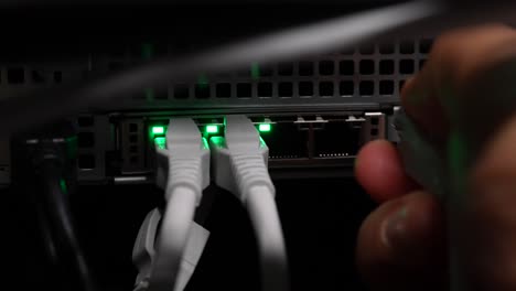 unplugging four networking ethernet cables into network server switch by hand, close up shot