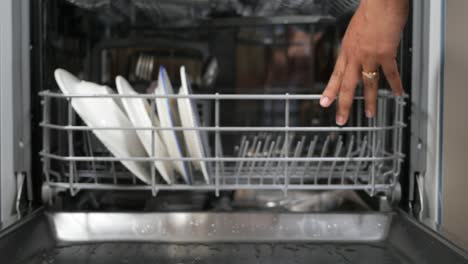 person opening a dishwasher with dishes inside