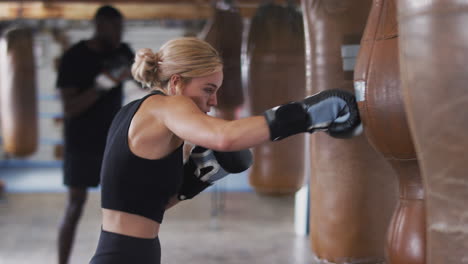 Boxerin-Im-Fitnessstudio-Trainiert-Mit-Altmodischem-Boxsack-Aus-Leder