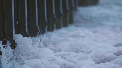 waves crash along the metal sea wall of the great lakes. rain falls during the grey day on the edge of the midwest.