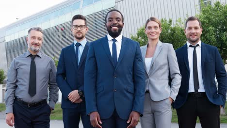 vista de cerca de un grupo de empresarios multiétnicos con ropa elegante sonriendo y mirando la cámara en la calle