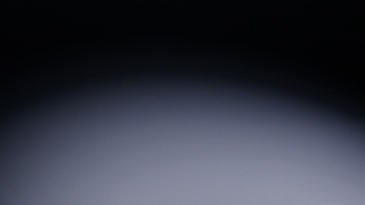 Slow-motion wide shot of red die rolling into the middle of the screen from the right and stopping