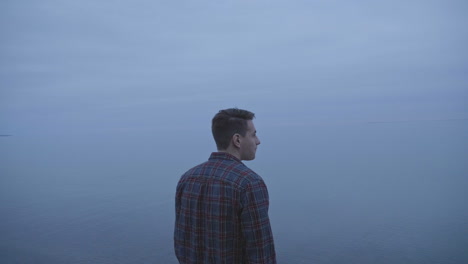 caucasian man standing next to a foggy lake